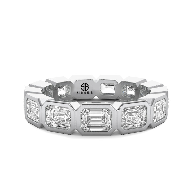 An elongated eternity band anniversary ring with emerald cut lab diamonds set in a white gold band, featuring a bezel setting.