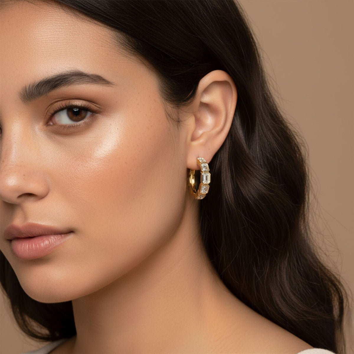 Angled portrait of a model wearing yellow gold emerald-cut diamond hoop earrings