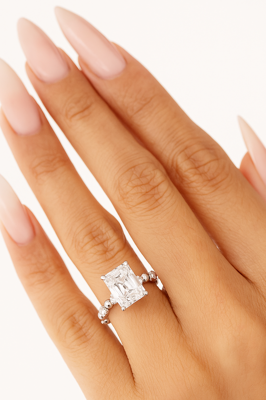 Radiant cut lab diamond engagement ring in 14K gold with beaded band, worn on hand against a neutral background