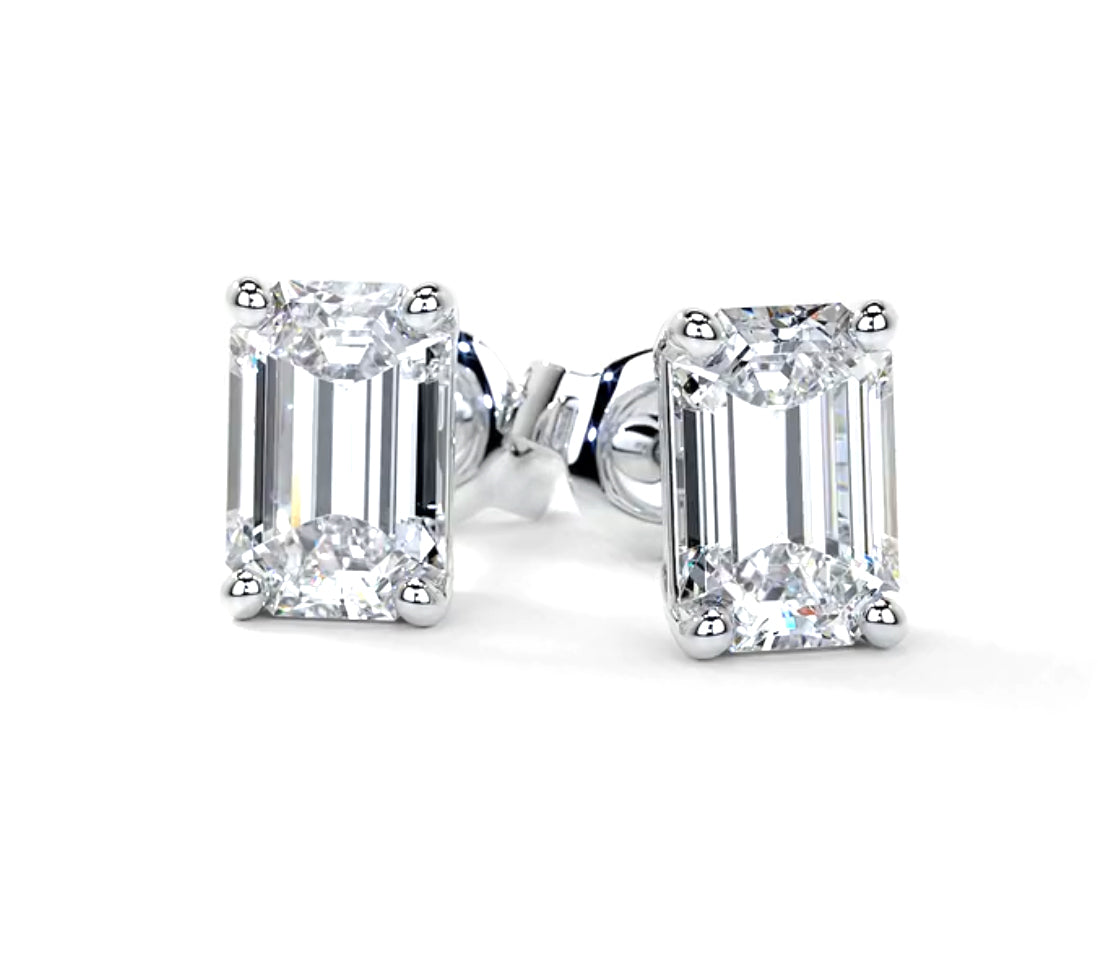 A pair of emerald cut diamond stud earrings set in 14k white gold with a clear and clean appearance.