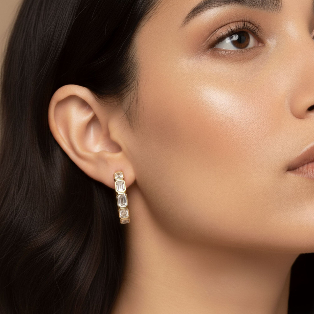 Close-up of a model wearing a yellow gold emerald-cut diamond bezel hoop earring