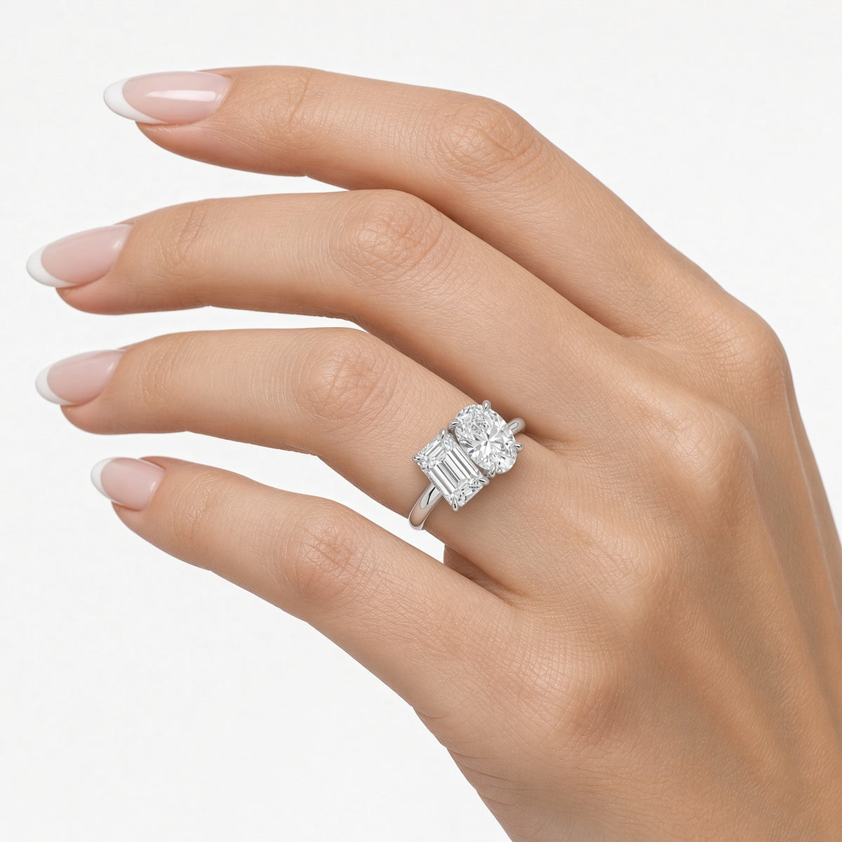 Emerald and oval lab-grown diamond engagement ring worn on hand