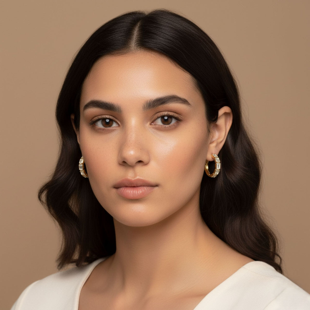 Model wearing yellow gold emerald-cut diamond hoop earrings, showing their size and appearance