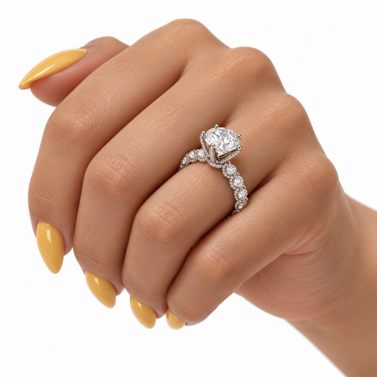     White gold round diamond engagement ring on a relaxed female hand with long citrine-yellow almond nails.